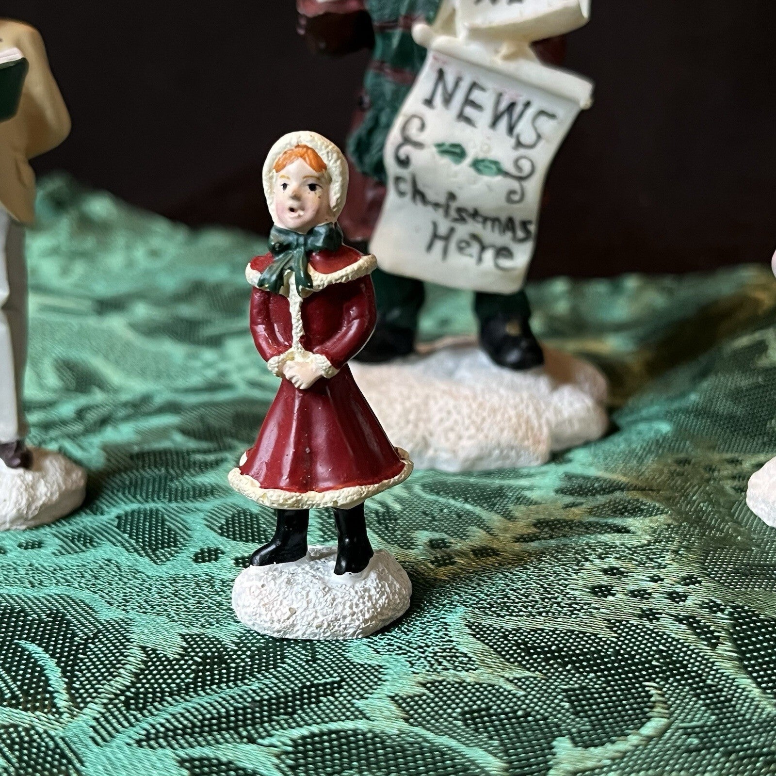 Miniature Christmas figurines including Christmas carolers and newspaper seller