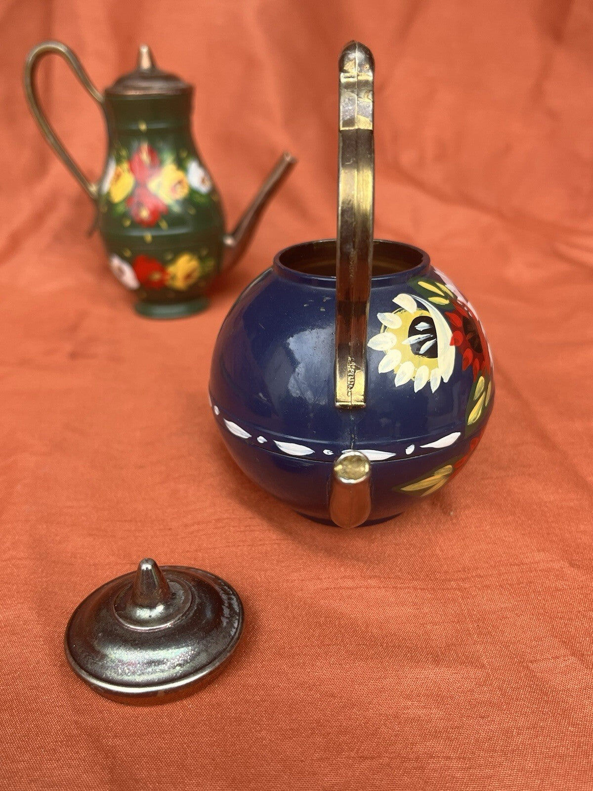 hand-painted metal teapots featuring colorful floral designs. Fun decor