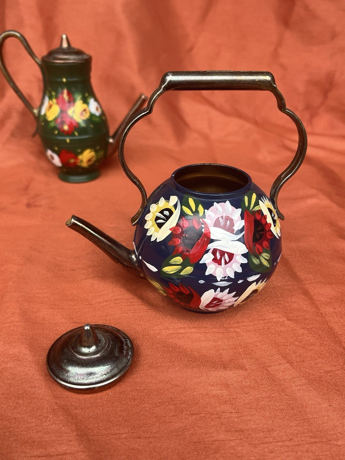 hand-painted metal teapots featuring colorful floral designs. Fun decor