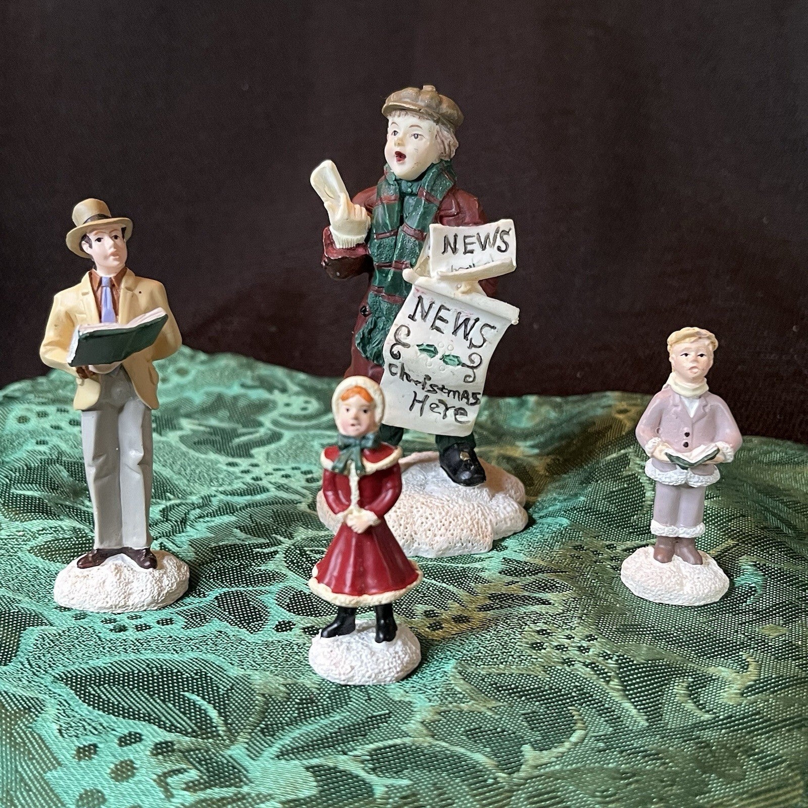 Miniature Christmas figurines including Christmas carolers and newspaper seller