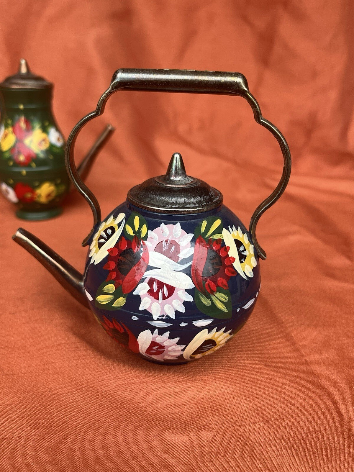 hand-painted metal teapots featuring colorful floral designs. Fun decor