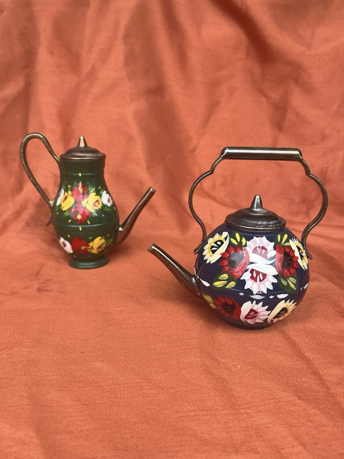hand-painted metal teapots featuring colorful floral designs. Fun decor