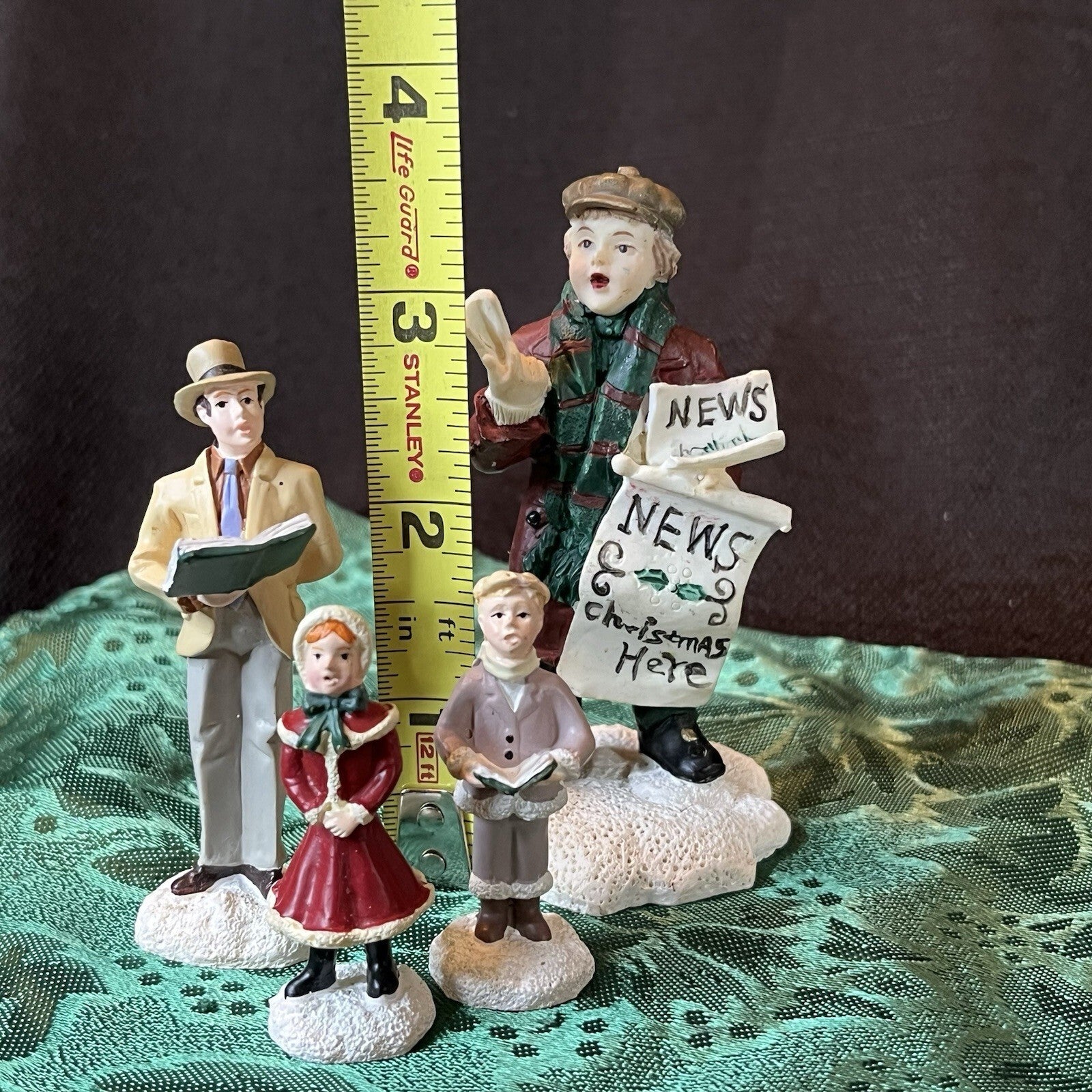 Miniature Christmas figurines including Christmas carolers and newspaper seller
