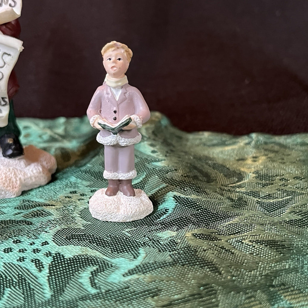 Miniature Christmas figurines including Christmas carolers and newspaper seller