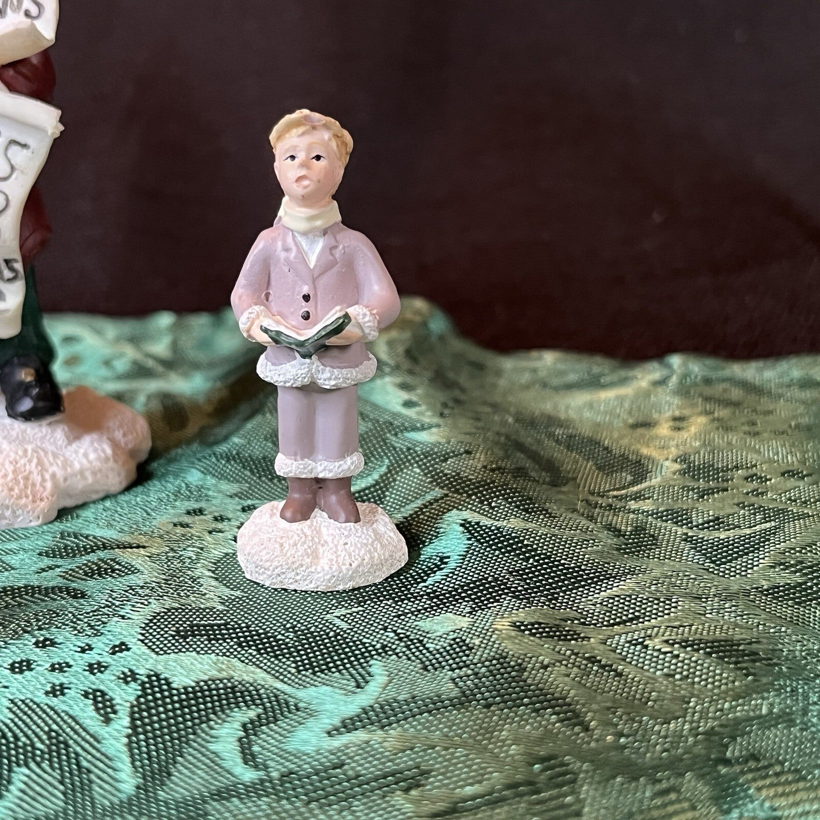 Miniature Christmas figurines including Christmas carolers and newspaper seller