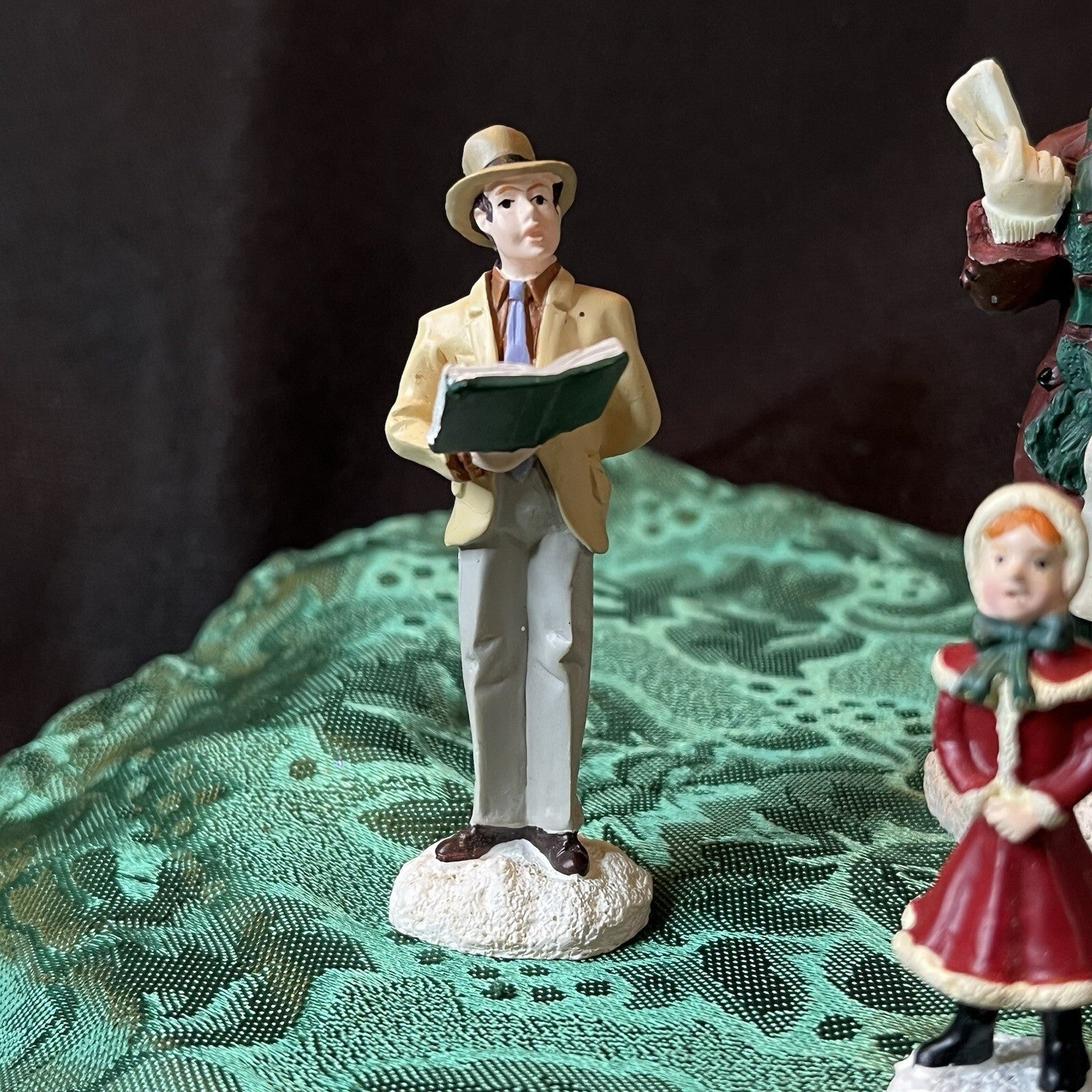 Miniature Christmas figurines including Christmas carolers and newspaper seller